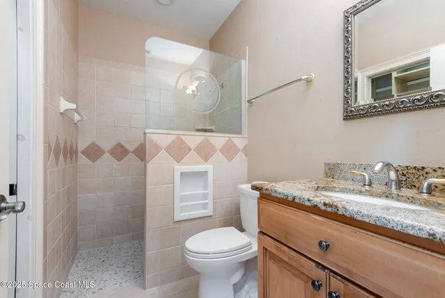 a bathroom with a granite countertop sink mirror vanity and toilet