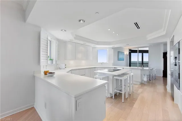 a view of a kitchen with kitchen island a sink a stove a dining table and chairs