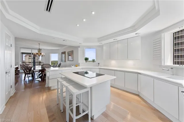 a kitchen with white cabinets appliances and dining table