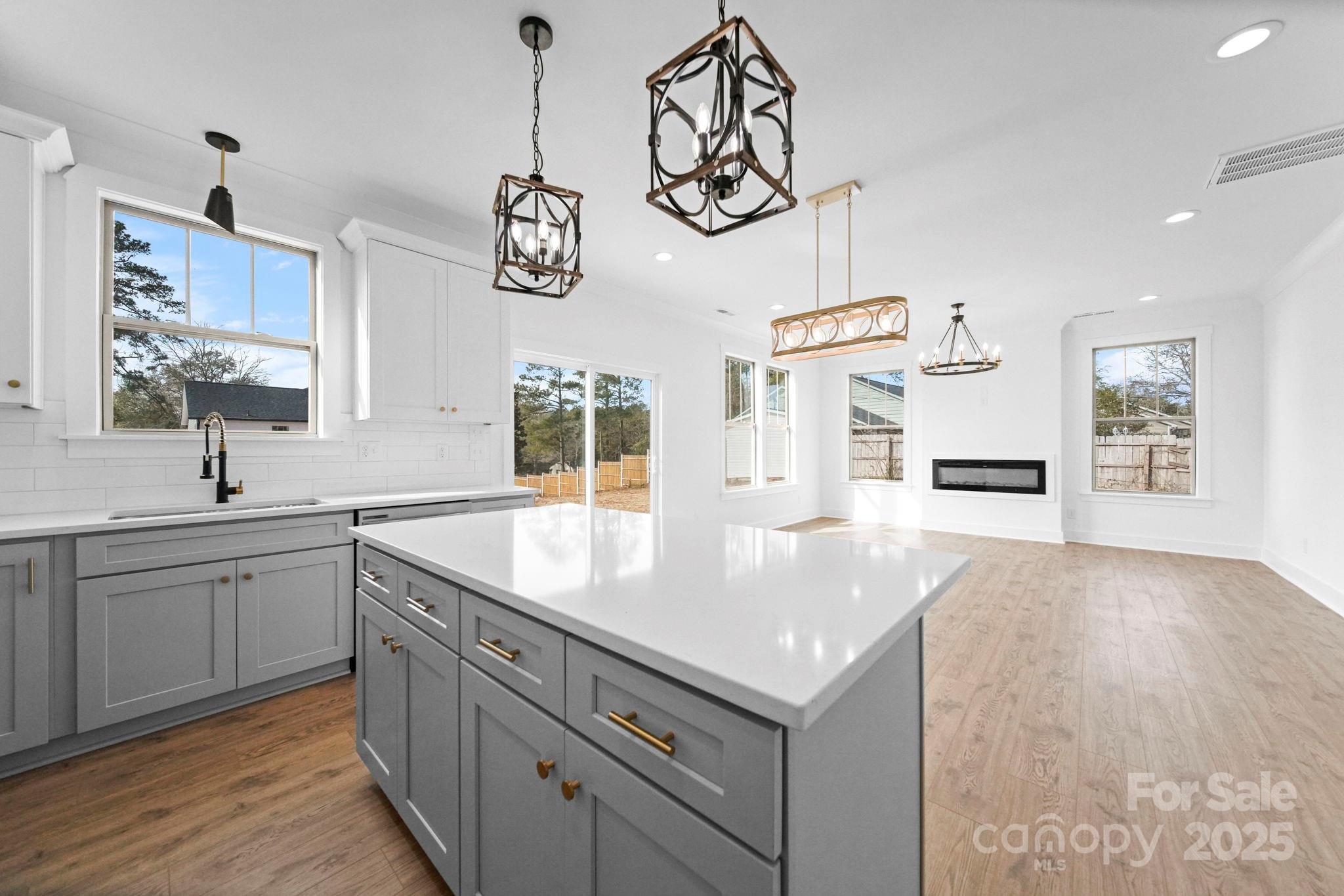 a kitchen with a sink chandelier and wooden floor