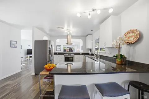 a kitchen with stainless steel appliances granite countertop a sink refrigerator dining table and chairs