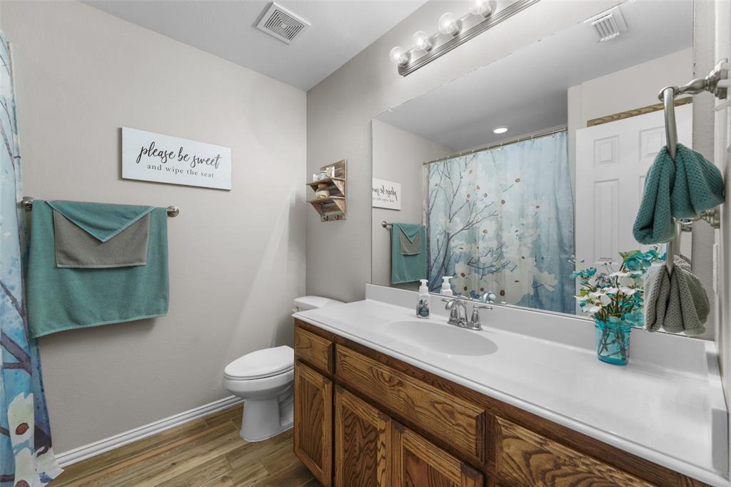 102 Avery Lane Fate, TX 75189 - Photo 19 of 30 a bathroom with a granite countertop sink a toilet a mirror and shower