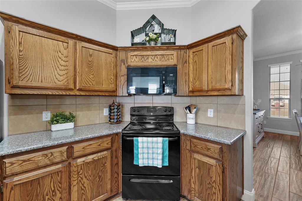 102 Avery Lane Fate, TX 75189 - Photo 10 of 30 a kitchen with granite countertop a stove top oven cabinetry a chimney and cabinets