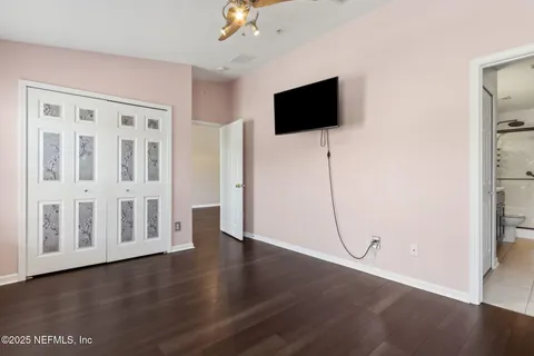 a view of an empty room with wooden floor and a flat screen tv