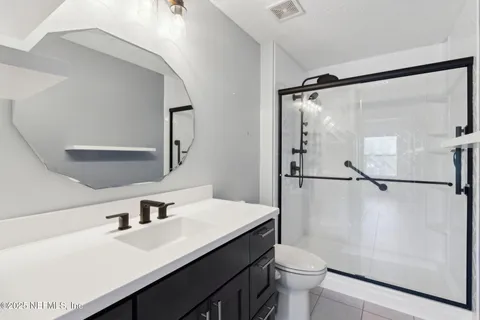 a bathroom with a sink a toilet a mirror and shower