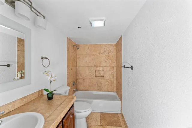 a bathroom with a granite countertop sink a toilet and shower