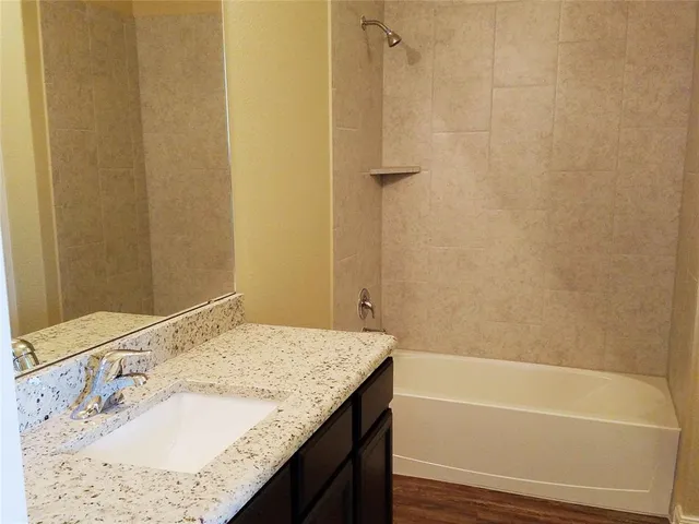 a bathroom with a granite countertop sink and a bathtub