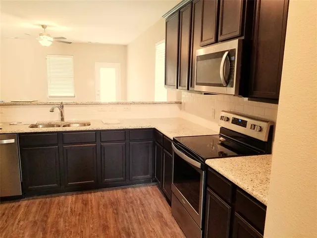 a kitchen with granite countertop a sink cabinets and stainless steel appliances