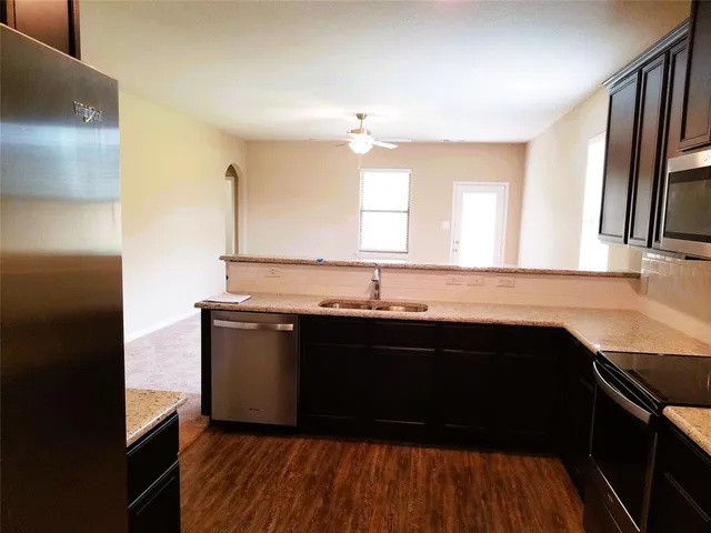 a kitchen with a sink dishwasher a refrigerator and wooden floor