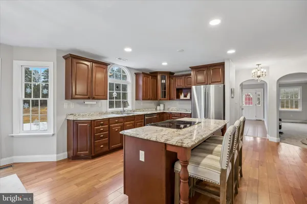 a kitchen with stainless steel appliances granite countertop a kitchen island hardwood floor sink stove and granite counter top