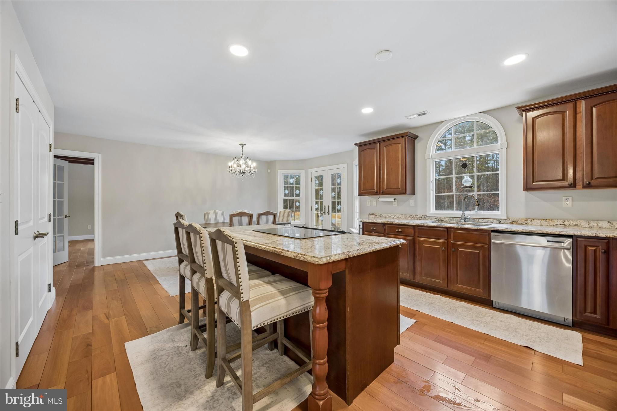 883 Atsion Road Shamong, NJ 08088 - Photo 18 of 42 a kitchen with granite countertop lots of wooden cabinets a sink dishwasher a dining table and chairs with wooden floor