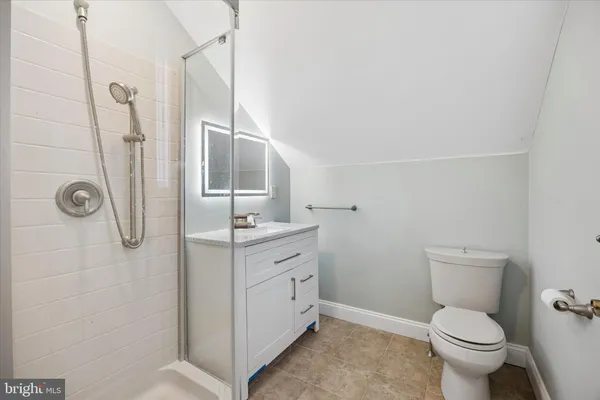 a bathroom with a granite countertop toilet a sink a mirror and shower
