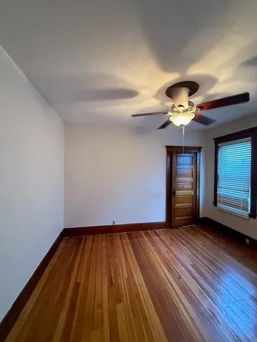 a view of an empty room with wooden floor and window