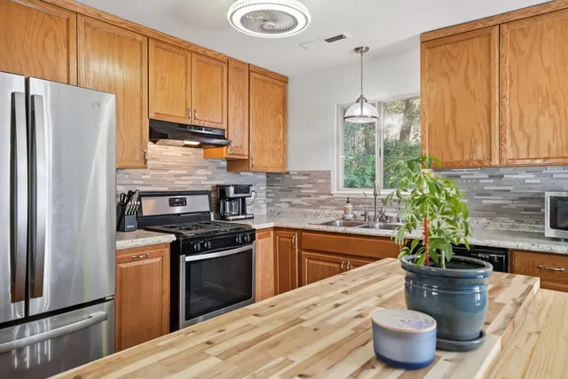 a kitchen with stainless steel appliances kitchen island granite countertop a refrigerator a stove a sink and cabinets