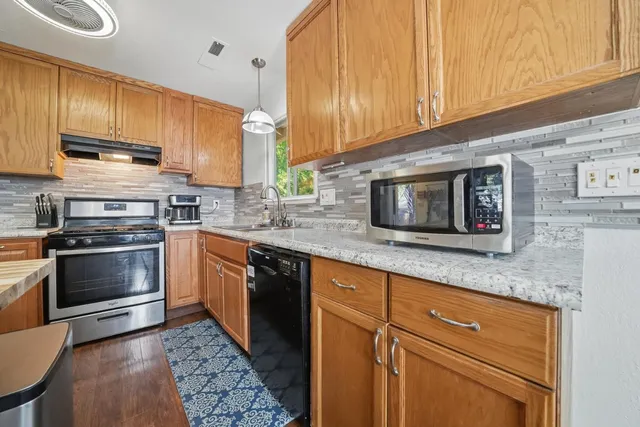 a kitchen with stainless steel appliances granite countertop a stove a sink and a microwave