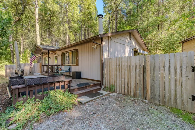 a backyard of a house with wooden fence and large trees