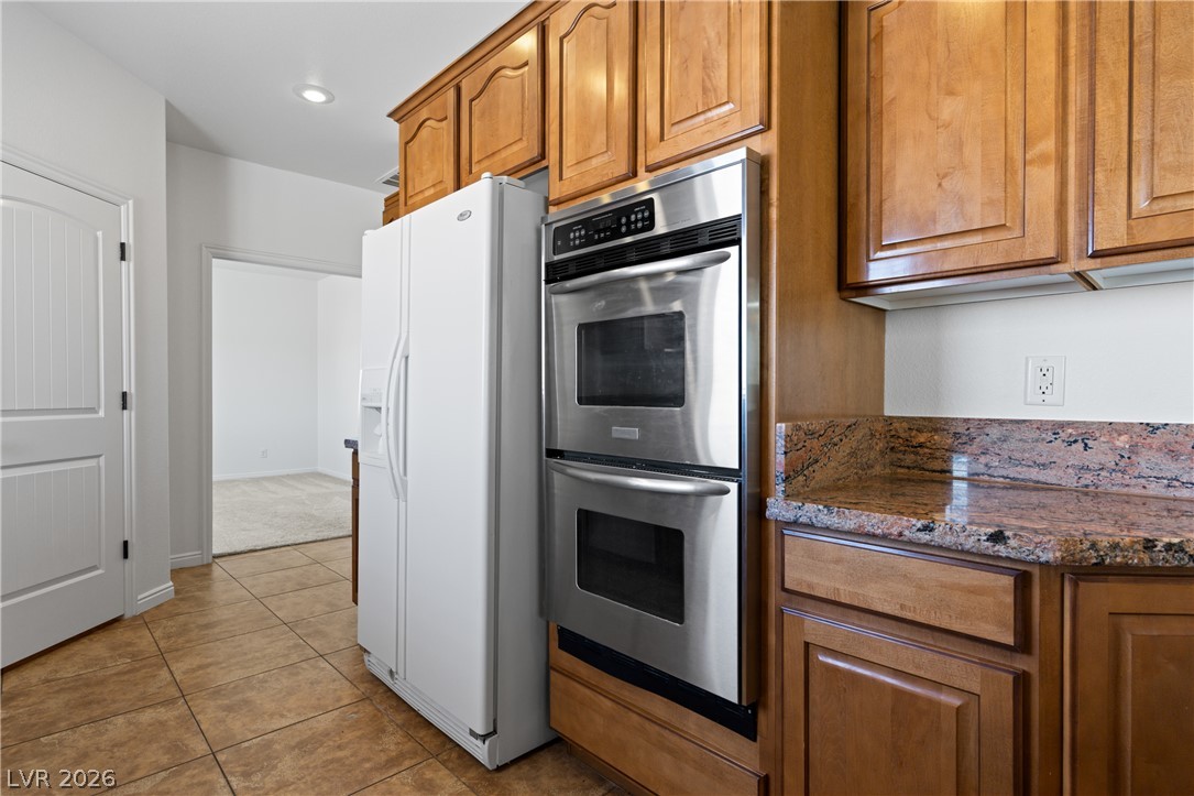 575 Gann Avenue Logandale, NV 89021 - Photo 20 of 75 Warm wood cabinetry and granite countertops frame a sleek double oven and built-in refrigerator.