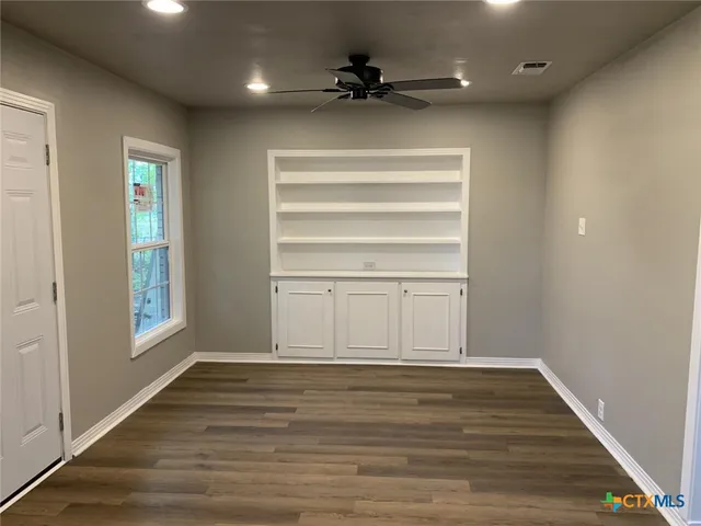 a view of an empty room with a window and wooden floor