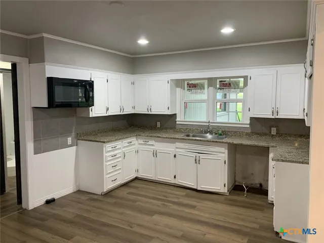 a kitchen with granite countertop a stove a sink and a microwave