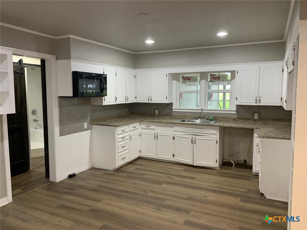 1902 State Highway 95 Little River-Academy, TX 76554 - Photo 8 of 20 a kitchen with granite countertop a refrigerator a sink and white cabinets
