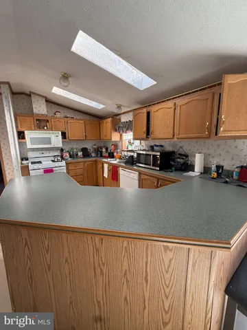 a kitchen with stainless steel appliances granite countertop a refrigerator a sink dishwasher a stove a dining table and chairs with wooden floor