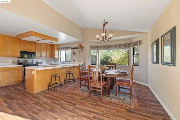 a kitchen with stainless steel appliances granite countertop wooden cabinets a sink dishwasher a stove and a refrigerator with wooden floor