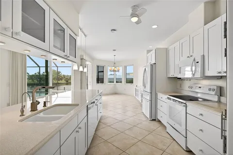 a large white kitchen with granite countertop a sink and cabinets