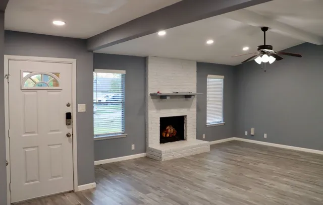 an empty room with windows fireplace and wooden floor