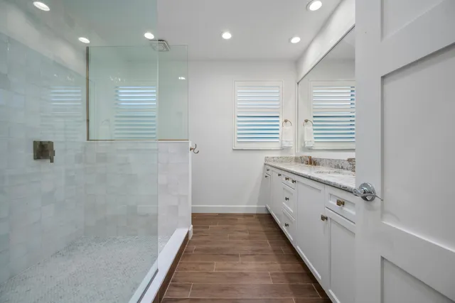 a bathroom with a granite countertop sink a toilet a mirror and a shower