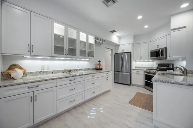 a kitchen with granite countertop cabinets stainless steel appliances a sink and a window
