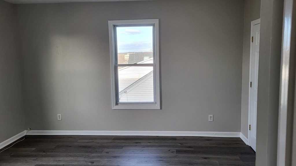 124 Stevens Street, Unit 3 Lowell, MA 01851 - Photo 15 of 18 an empty room with wooden floor and windows