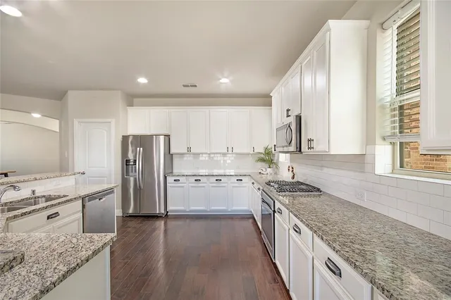 a kitchen with a center island wooden floor and stainless steel appliances