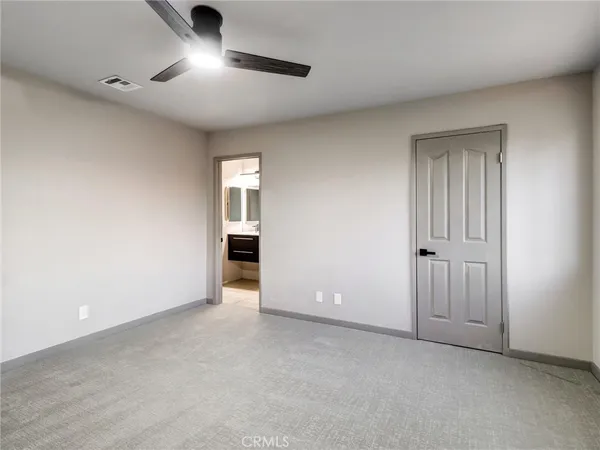 an empty room with ceiling fan and windows