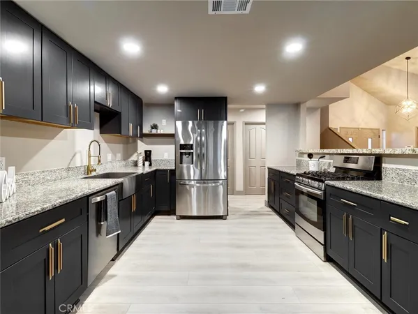 a large kitchen with stainless steel appliances kitchen island granite countertop a large counter top cabinets a sink and a counter top space