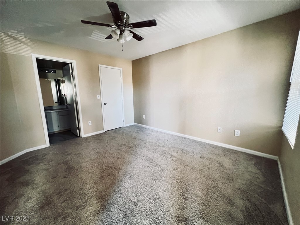 8101 West Flamingo Road, Unit 2161 Las Vegas, NV 89147 - Photo 13 of 21 Unfurnished bedroom featuring dark carpet, ceiling fan, and ensuite bathroom
