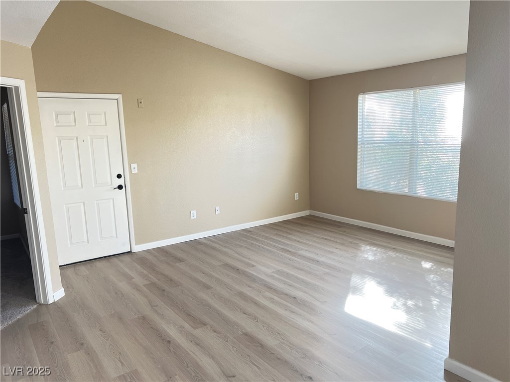 8101 West Flamingo Road, Unit 2161 Las Vegas, NV 89147 - Photo 2 of 21 Empty room with light wood-style flooring and vaulted ceiling