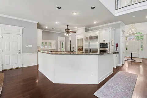 a kitchen with stainless steel appliances granite countertop a refrigerator a sink and white cabinets