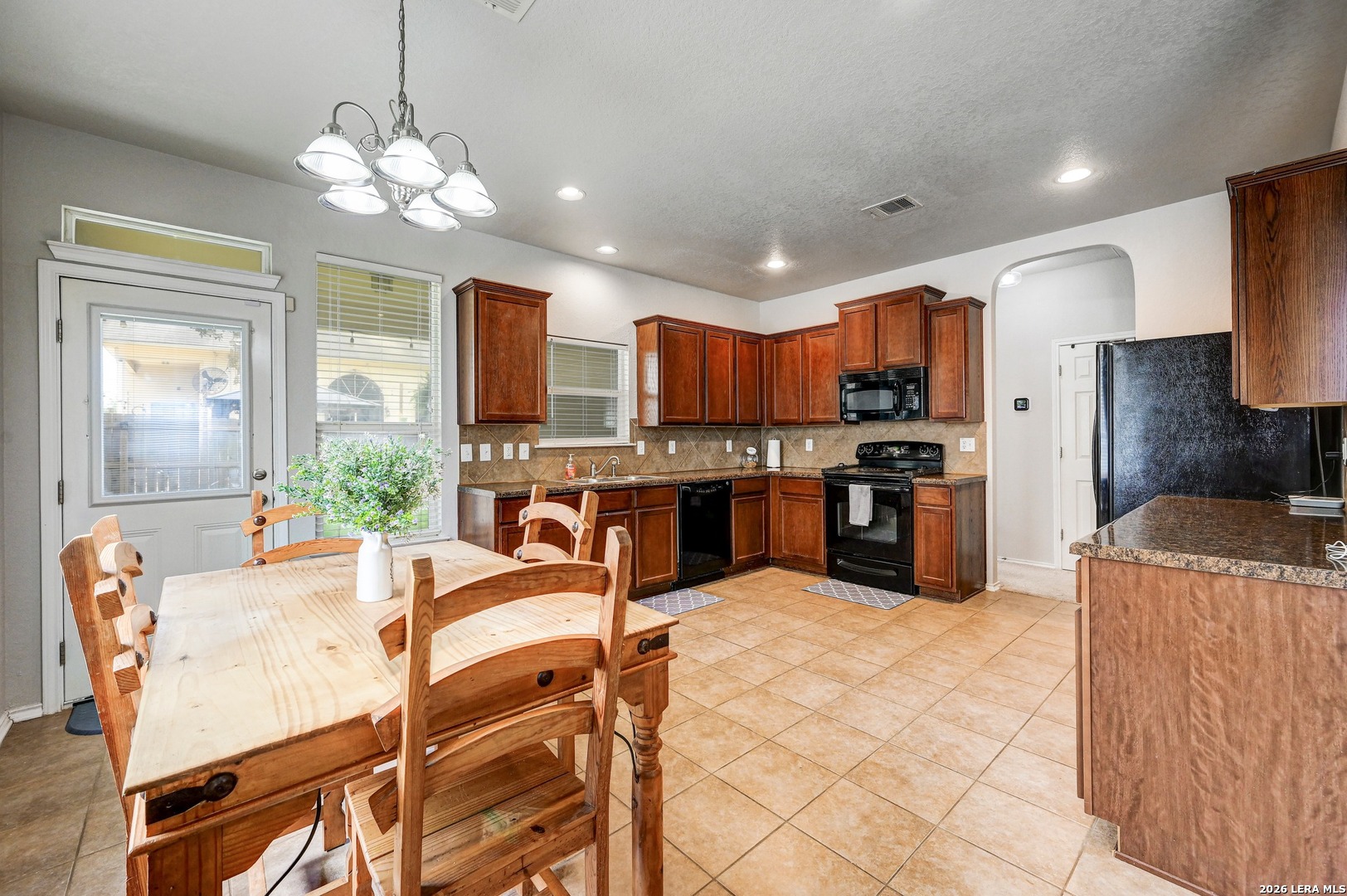 720 Hollow Ridge Schertz, TX 78108 - Photo 11 of 27 a kitchen with stainless steel appliances kitchen island granite countertop a refrigerator a stove a sink a dining table and chairs with wooden floor
