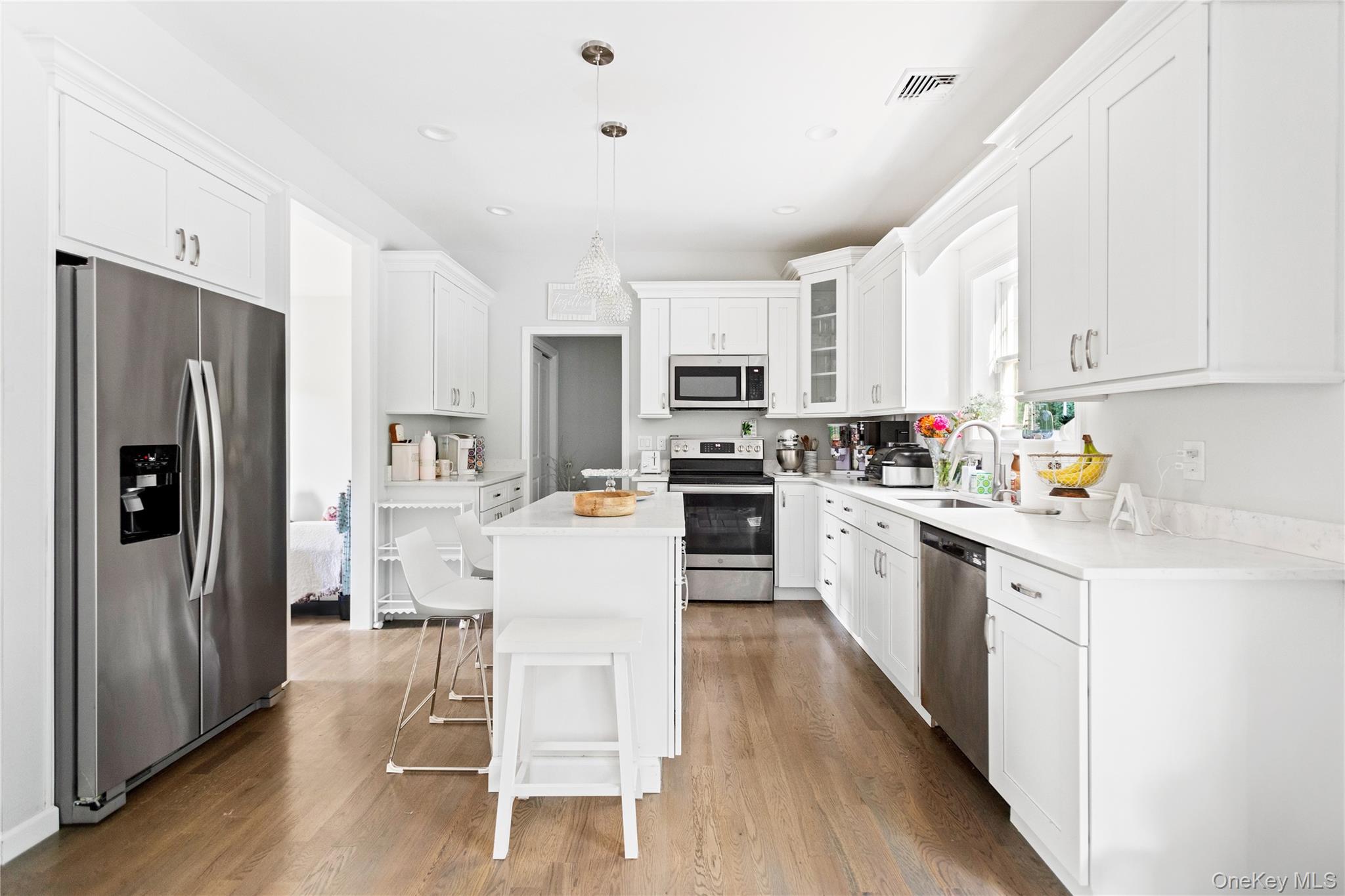24 Belmont Road Sound Beach, NY 11789 - Photo 4 of 23 a kitchen with white cabinets and stainless steel appliances