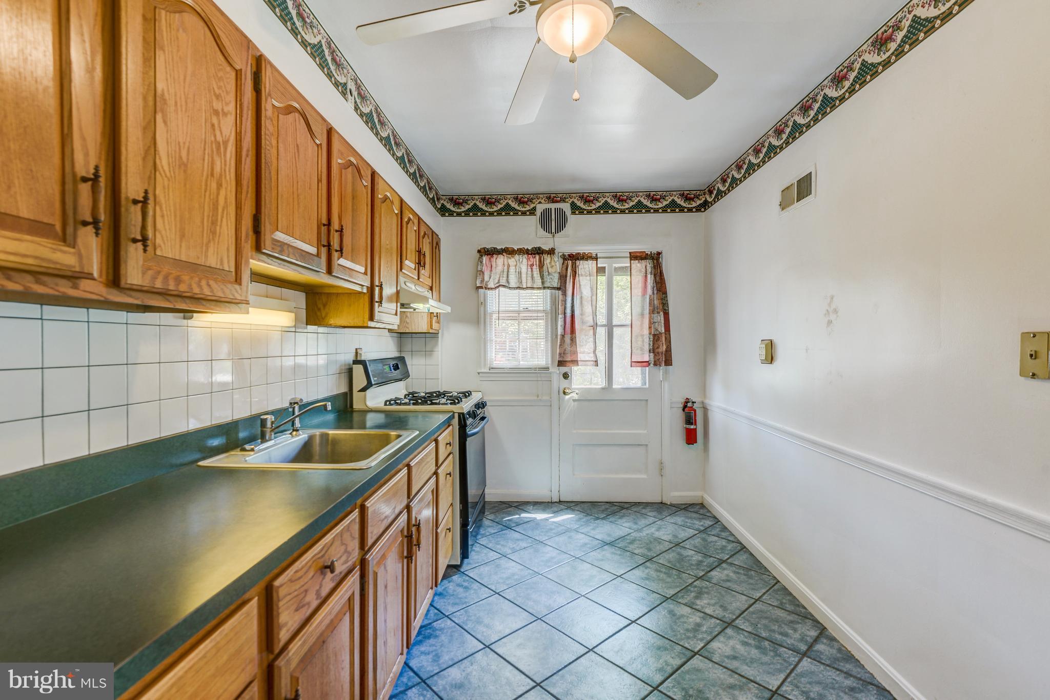 1265 Cedarcroft Road Baltimore, MD 21239 - Photo 11 of 21 a kitchen with a sink and wooden cabinets