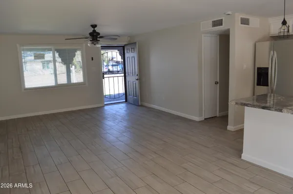 a view of an empty room with window and wooden floor