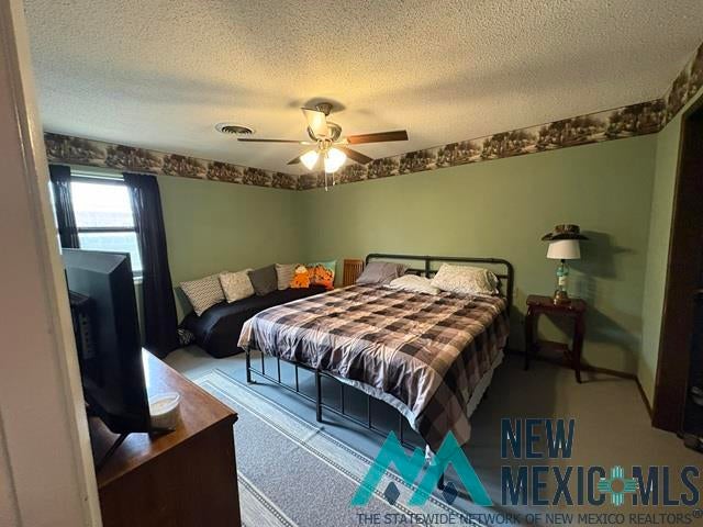 1037 Oakhurst Road Clovis, NM 88101 - Photo 8 of 21 Bedroom featuring light green walls, a single window with dark drapery, ceiling fan with integrated lighting, and a textured ceiling