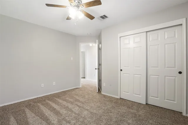 a view of an empty room and chandelier fan