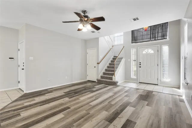 a view of an empty room with wooden floor and stairs