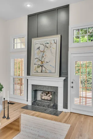 an empty room with wooden floor fireplace and windows