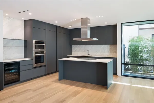 a kitchen with kitchen island stainless steel appliances a sink cabinets and wooden floor