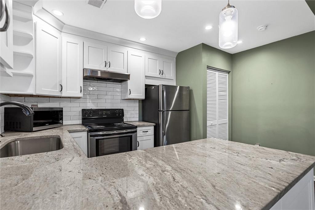 144 Woodmere Square Northwest Atlanta, GA 30327 - Photo 14 of 39 a kitchen with stainless steel appliances granite countertop a refrigerator a stove a sink and a microwave