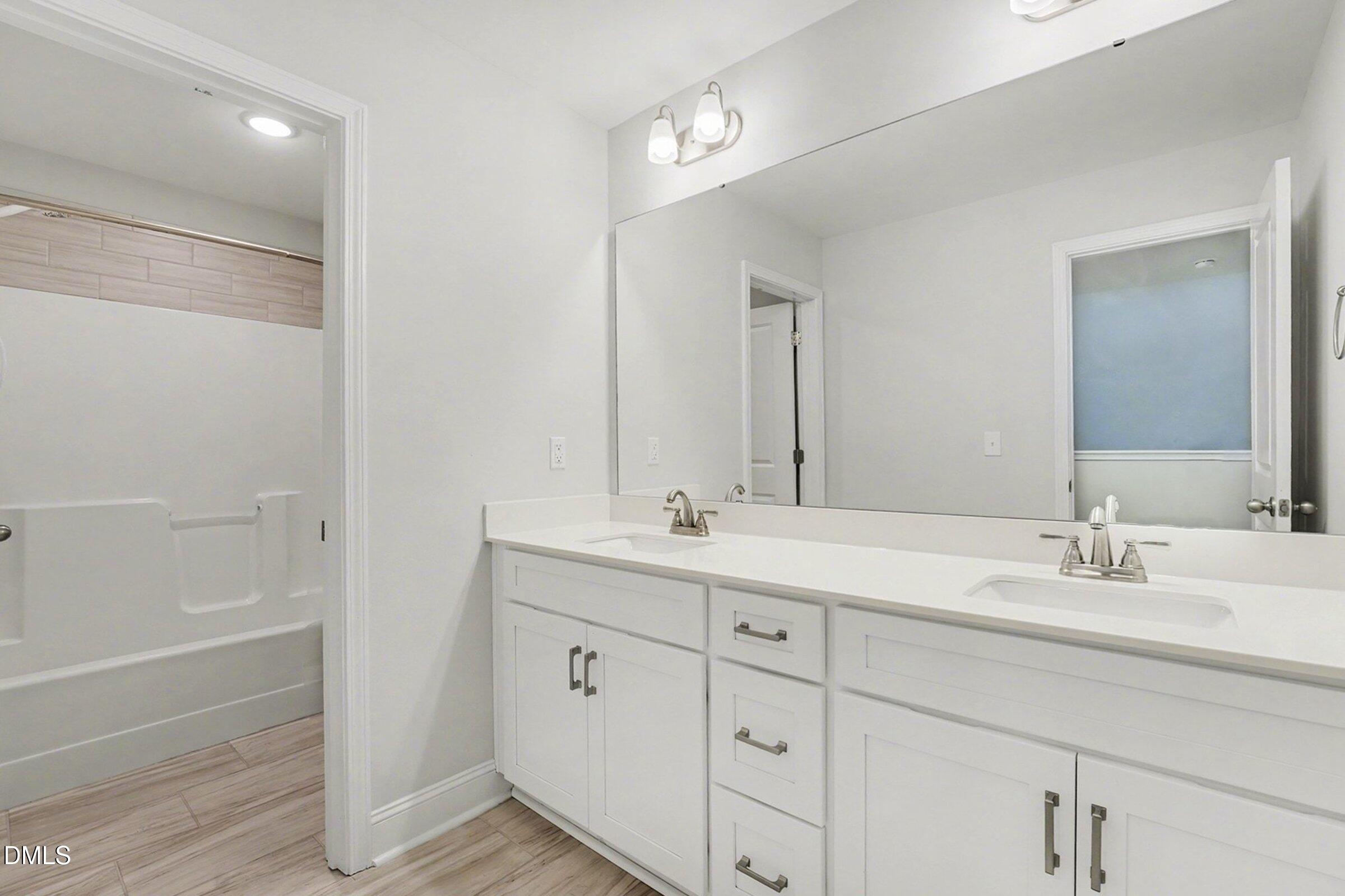2815 Lemuel Black Road Spring Lake, NC 28390 - Photo 27 of 37 a bathroom with a double vanity sink a mirror and a bathtub