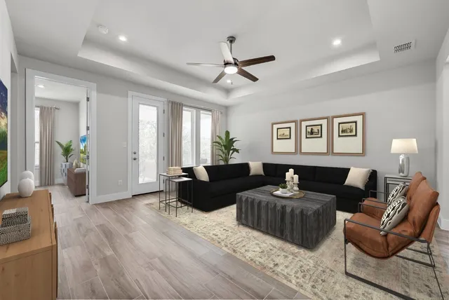 a living room with furniture a ceiling fan a lamp and a window