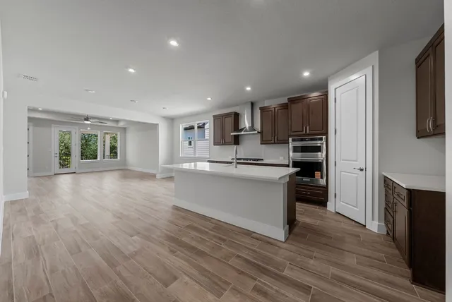 a large kitchen with kitchen island a sink wooden floor and a refrigerator
